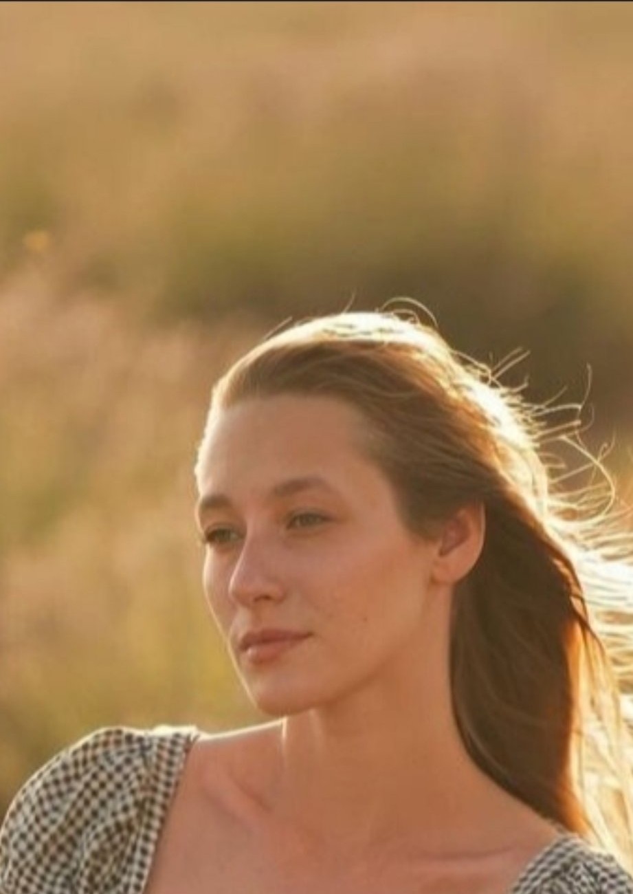 Dasha in golden-hour light in a field, her long light-brown hair lit by the sun, holding a bunch of lavender