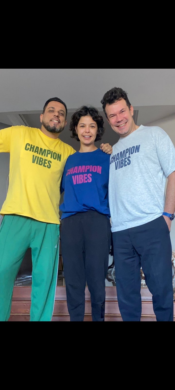 Three people standing together wearing yellow, blue and grey CHAMPION VIBES tees